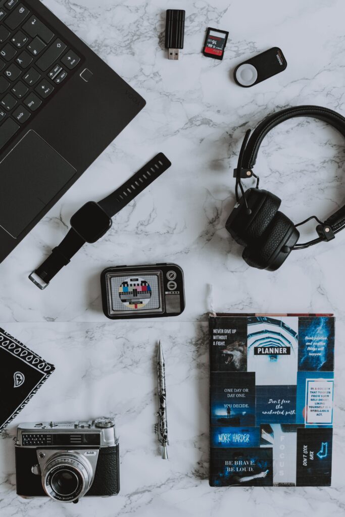 Gadgets de tecnologia modernos sobre a mesa, incluindo smartwatch, fone de ouvido sem fio e câmera fotográfica, ilustrando a página inicial do site Mundo dos Eletrônicos.